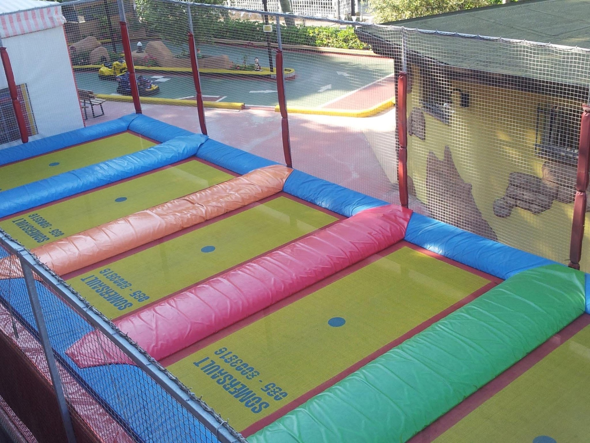 I sei trampolini del parco con bordi imbottiti colorati e rete di sicurezza