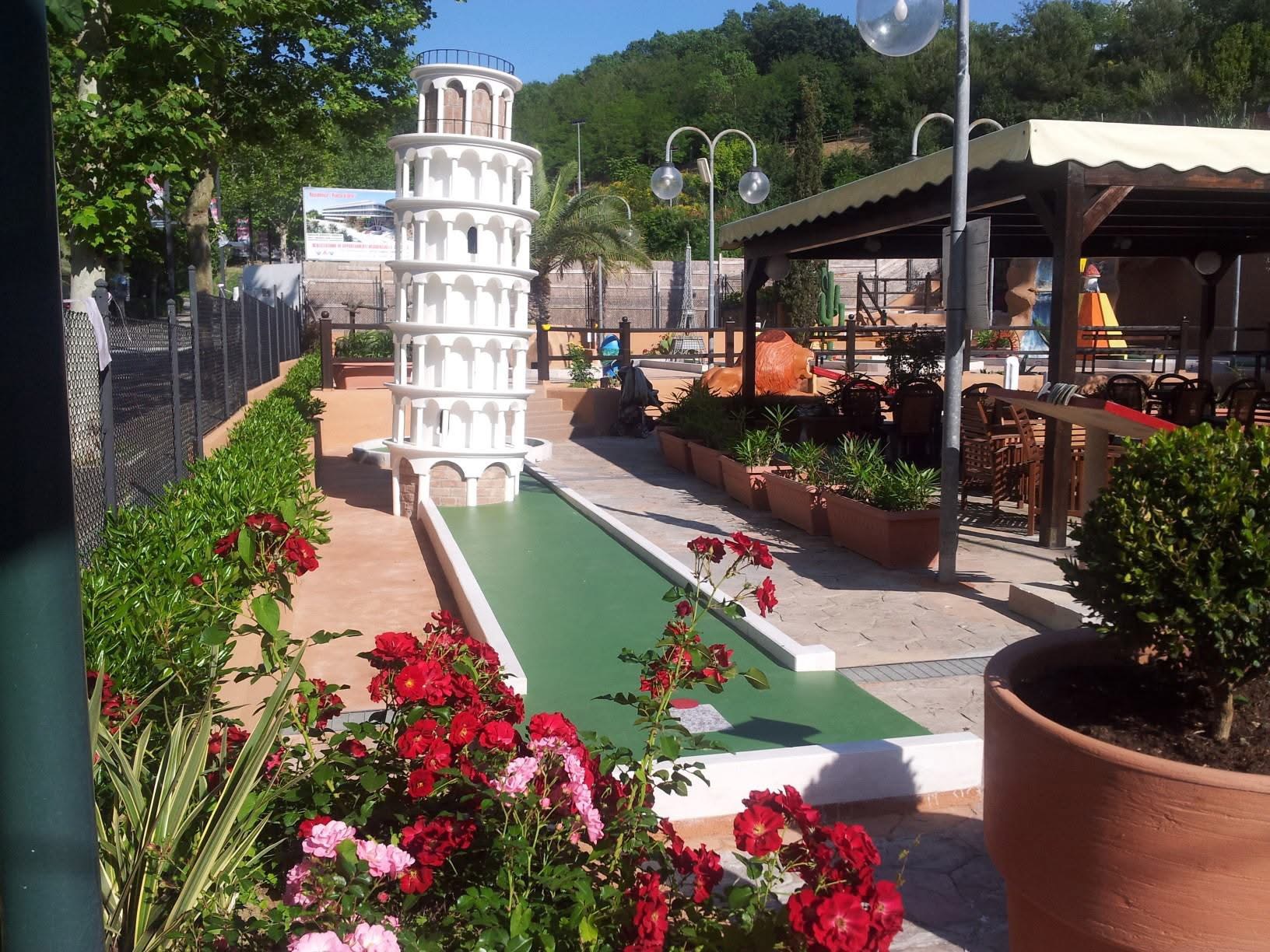 Una buca del minigolf del Garden Golf con la torre di Pisa in miniatura e le rose in fiore